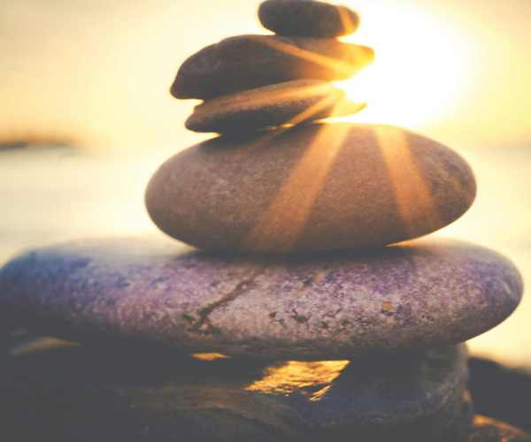 Innovation - stacked rocks with sun shining behind them.